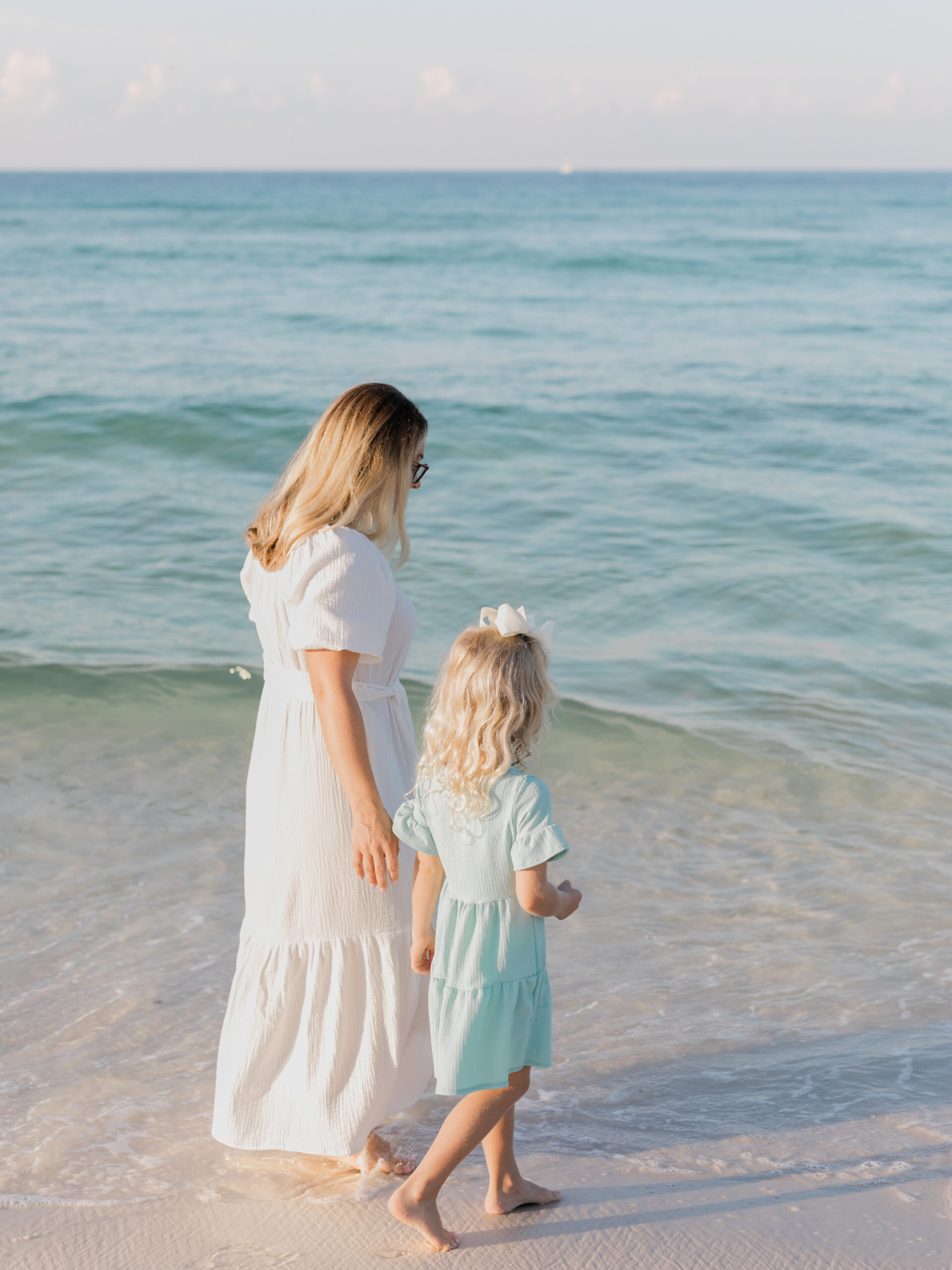 Mother and daughter walking along shoreline